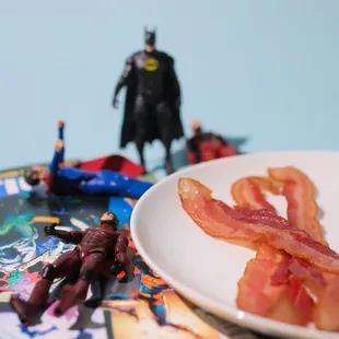 a plate of bacon and batman figurines
