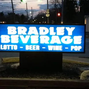 a sign for bradley beverage lit up at night