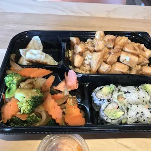 Bento box. Dumplings, vegetables, rice, chicken, and California roll.
