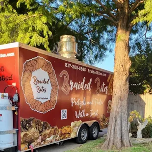 a food truck parked next to a tree