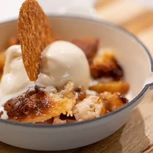 Seasonal peach cobbler served with vanilla bean ice cream.