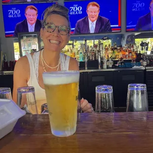 a woman sitting at a bar with a glass of beer