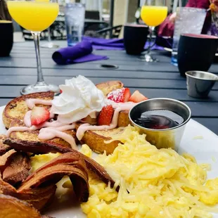 Strawberry shortcake French toast , eggs, and bacon. Mimosas in background.