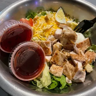 a salad with chicken, lettuce, cheese, and dressing