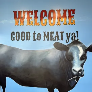 a cow in front of a welcome sign