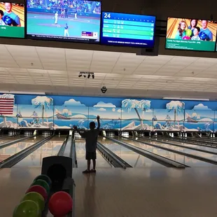 a boy standing in front of a bowling alley