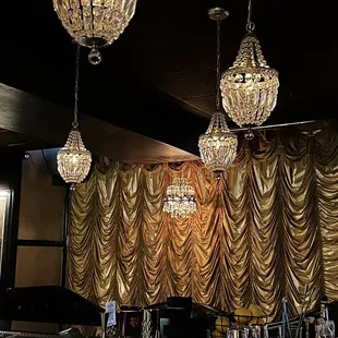 a stage with gold drapes and chandeliers