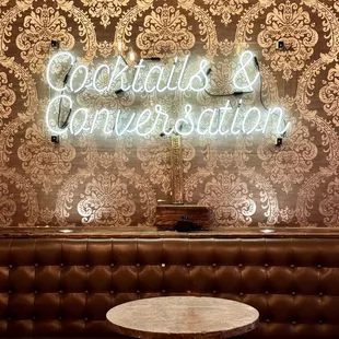 Neon/LED sign (cocktails and conversations) in the additional seating area near the second bar