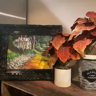 a potted plant and a painting on a shelf