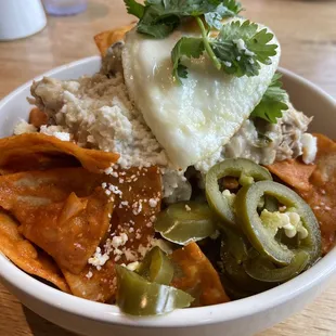 Smothered chicken chilaquiles with red sauce, jalapenos, and a fried egg