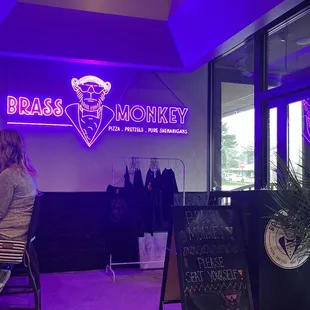 a woman sitting at a table in front of a neon sign