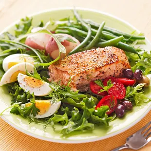 a plate of salad with salmon and eggs