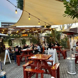 people sitting at tables under a shade