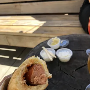 Smoked brat in their easy-to-eat roll/bread thing with onions and sauerkraut in the background