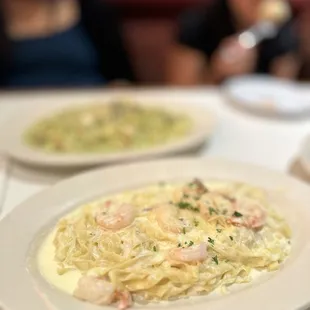 two plates of pasta and a woman in the background