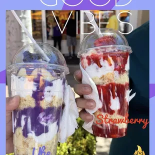 a hand holding a cup of ice cream and strawberries