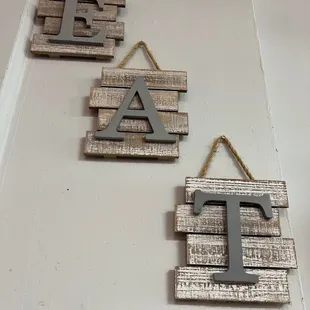 three wooden letters hanging on a wall