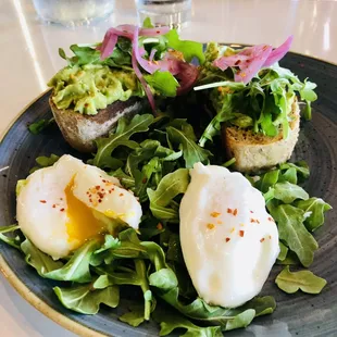 Bread with guacamole. Poached eggs, pickled onions, chili flakes.