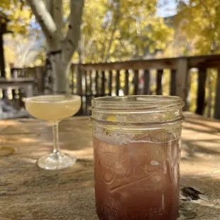 a jar of liquid and a drink on a picnic table