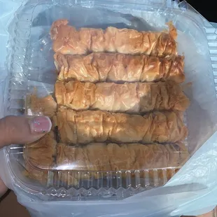 a person holding a plastic container filled with pastries