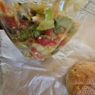 a bowl of salad and a roll