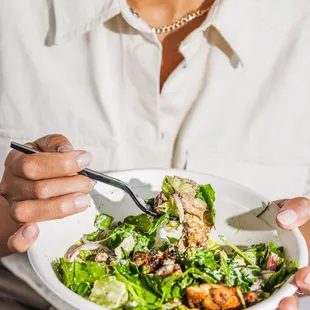 a woman holding a bowl of salad