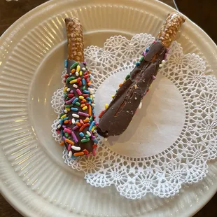 a chocolate and sprinkle donut on a paper plate