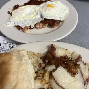 Corned beef hash with over medium eggs, homefries, and a biscuit