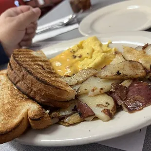 a plate of eggs, toast, potatoes, and sausage