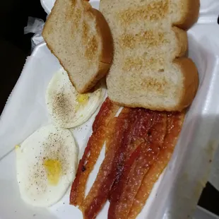 bacon, eggs, and toast in a styrofoam container