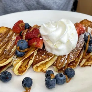 a plate of pancakes with whipped cream and berries