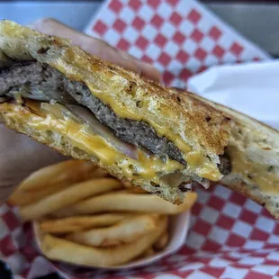 a hand holding a grilled cheeseburger