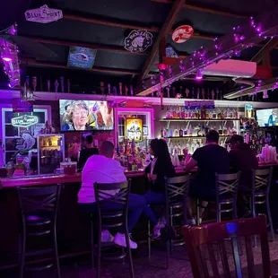 people sitting at a bar watching televisions