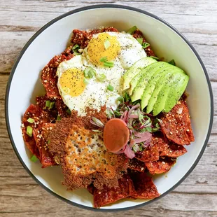Brekki Chilaquiles: Crispy corn chips tossed in red or green chile, topped with eggs, pickled onions, cilantro, and a side of smashed potato