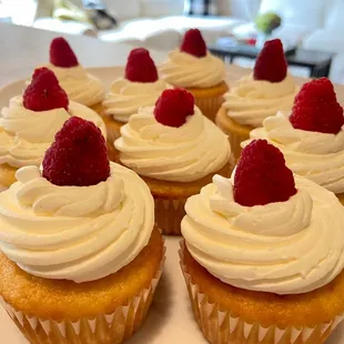 a plate of cupcakes with raspberries on top