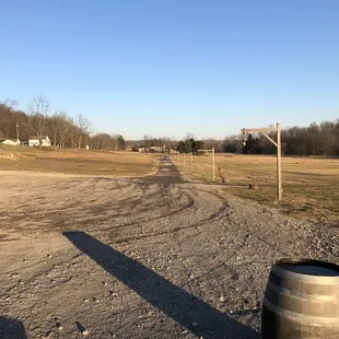 the shadow of a barrel on a dirt road