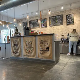 a woman standing at a counter in a coffee shop