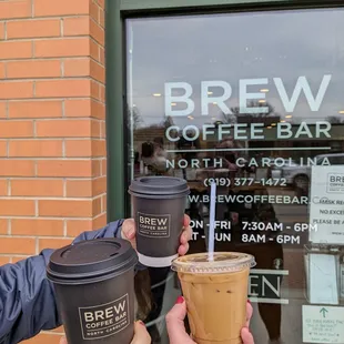 two people holding coffee cups in front of a window