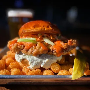 a chicken sandwich with tater tots and a pickle