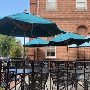 tables and umbrellas in front of a brick building