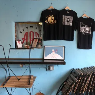 a rack of beer bottles and t - shirts on a blue wall