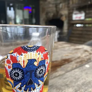 a glass of beer with a sugar skull on it