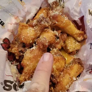 Basket of Very tiny Buffalo wings next to my pinky.