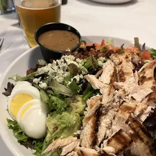 a salad with chicken, hard boiled eggs, and dressing