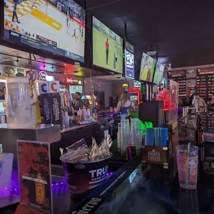 Corner bar seat at back entrance. Four TV's on each side, plugs under the bar. Draft list on the wall.