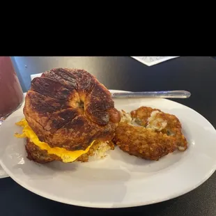 Classic Breakfast sandwich in croissant bread, scrambled eggs, American cheese, and side of potato pancake