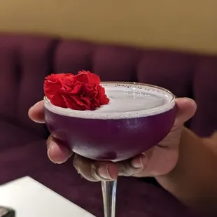 a person holding a purple cocktail