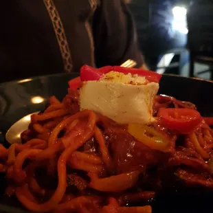 a bowl of spaghetti with a piece of cheese on top