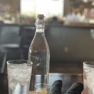 a glass of water, a bottle of water, and a napkin on a table