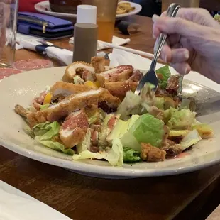 Fried chicken tenders slices on a salad.